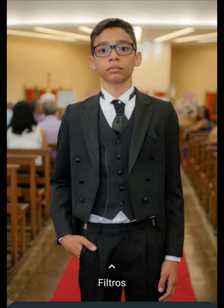 Foto de um garoto vestido com um terninho fino, de otima qualidade.